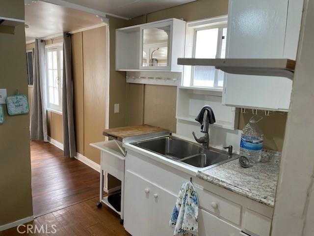 kitchen featuring a sink, baseboards, light countertops, white cabinets, and dark wood-style flooring