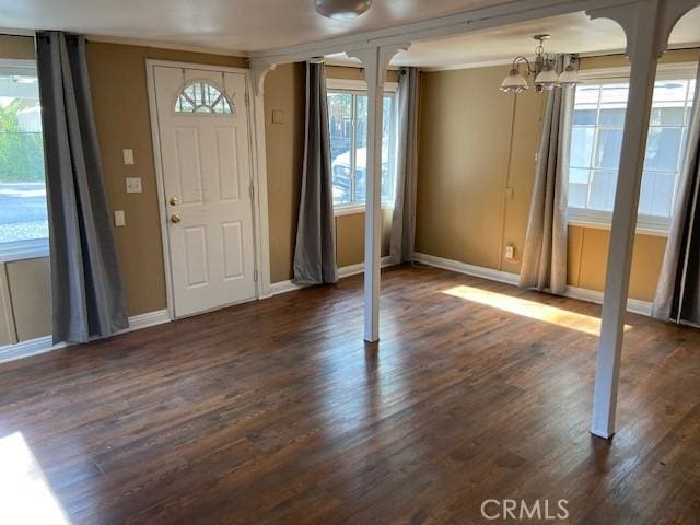 foyer entrance featuring dark wood finished floors, a chandelier, baseboards, and ornamental molding