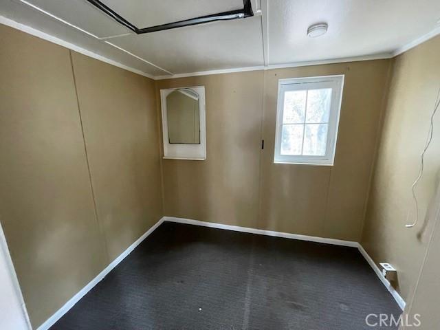 carpeted empty room with baseboards and crown molding