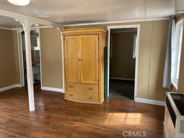 unfurnished bedroom with dark wood-type flooring, heating unit, and baseboards