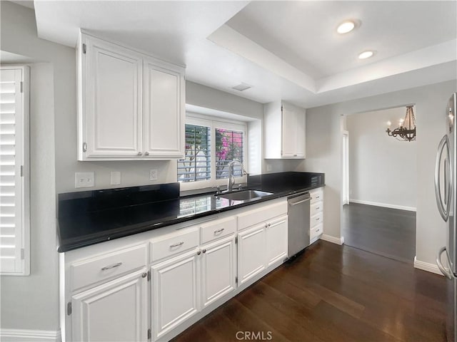 kitchen featuring appliances with stainless steel finishes, dark countertops, a sink, and white cabinets