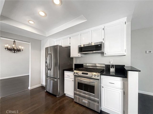 kitchen with stainless steel appliances, dark countertops, and white cabinets