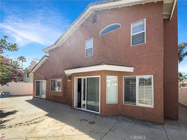 rear view of property featuring fence, a patio, and stucco siding