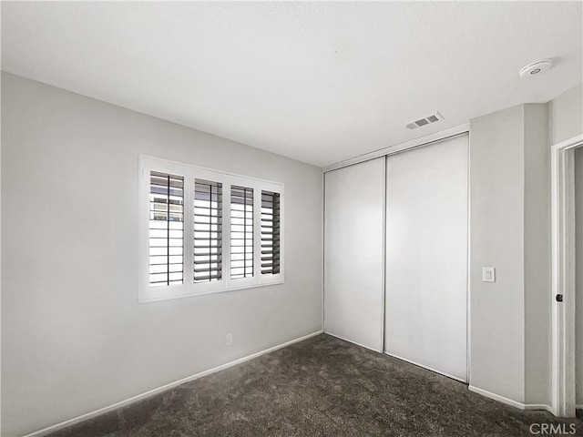 unfurnished bedroom featuring a closet, carpet flooring, visible vents, and baseboards