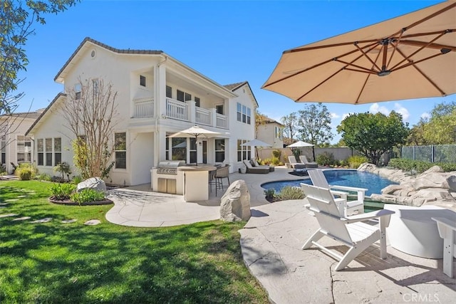 rear view of property featuring a lawn, outdoor dry bar, a patio, fence, and a balcony