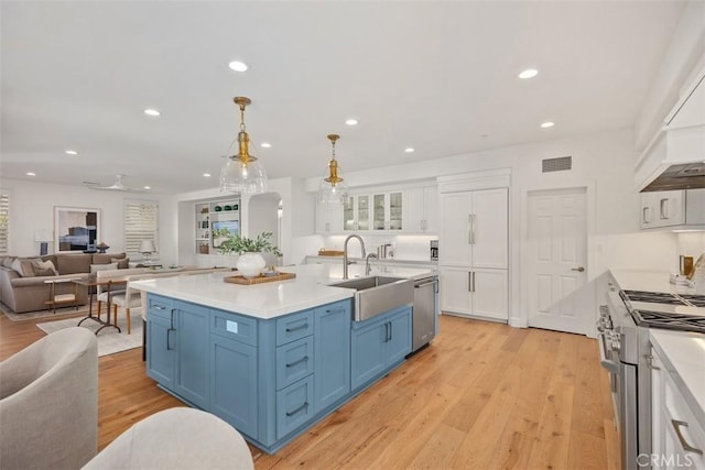 kitchen with a sink, white cabinets, appliances with stainless steel finishes, blue cabinets, and open floor plan