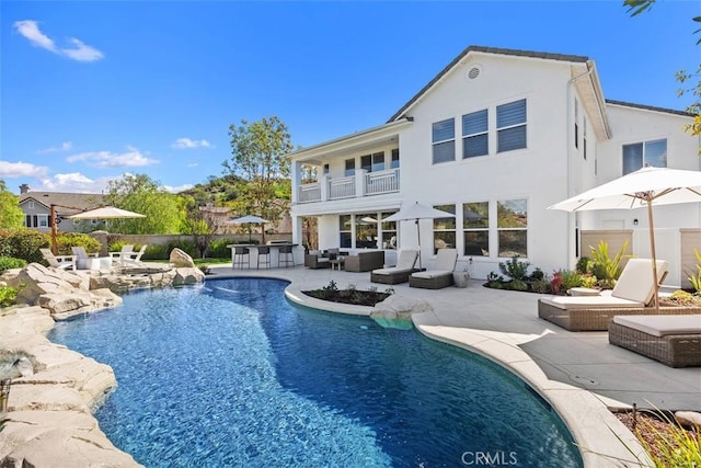 back of property with a patio, a balcony, stucco siding, an outdoor hangout area, and outdoor dry bar