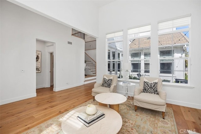 living area with stairway, plenty of natural light, baseboards, and wood finished floors