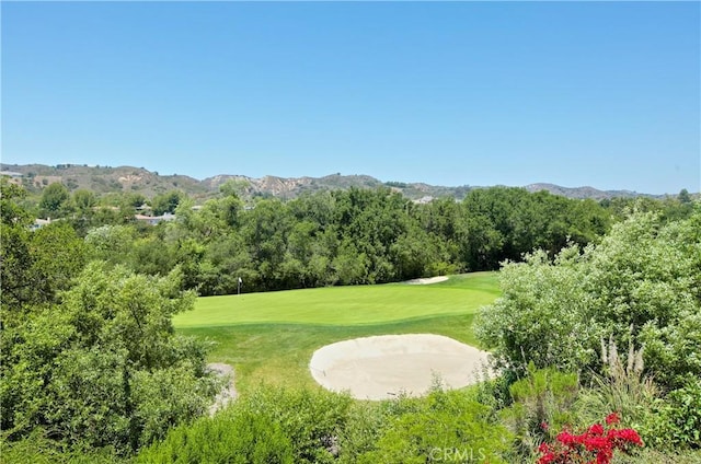 view of home's community with a mountain view, a lawn, and view of golf course