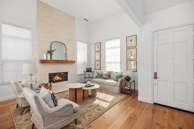 living area with visible vents, baseboards, wood finished floors, and a fireplace