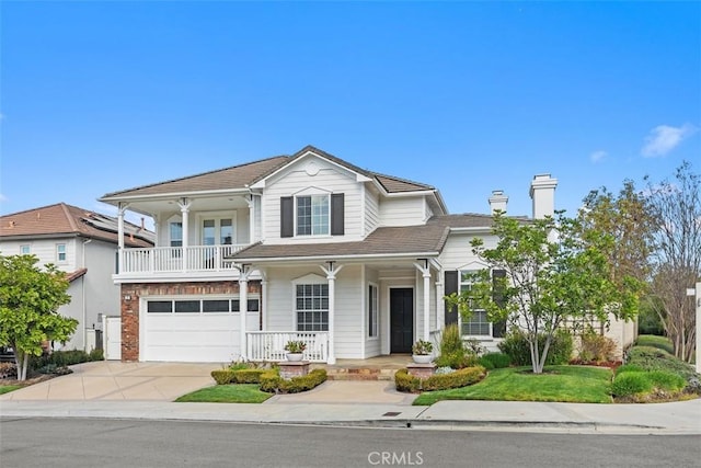 traditional-style home featuring a porch, concrete driveway, a chimney, a balcony, and a garage