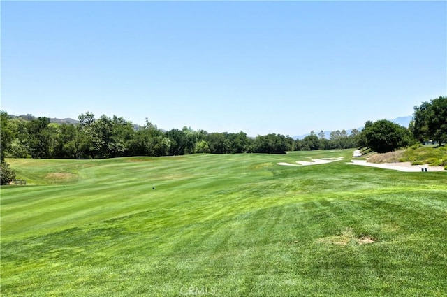 surrounding community with view of golf course and a yard