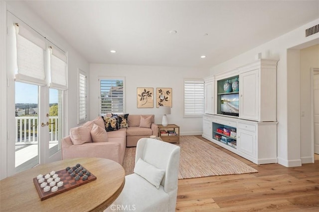 living room featuring a glass covered fireplace, recessed lighting, light wood-style floors, and baseboards