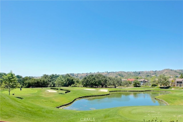 view of home's community with a water view, a lawn, and view of golf course