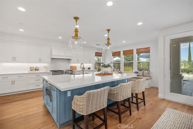 kitchen featuring light wood finished floors, white cabinets, and a sink