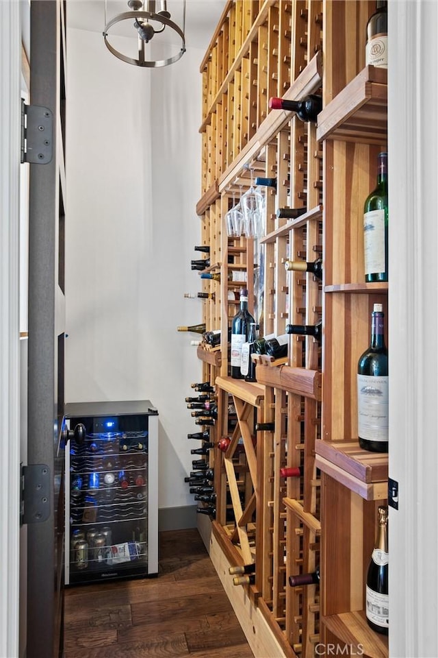 wine cellar with beverage cooler, wood finished floors, and baseboards