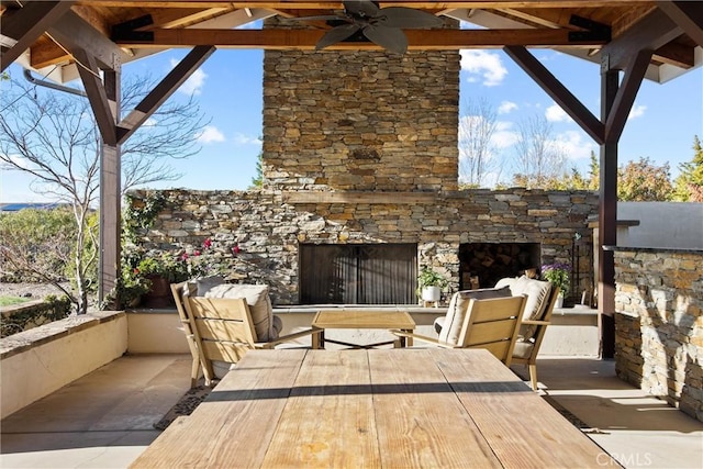 deck with a patio area, an outdoor stone fireplace, a ceiling fan, and outdoor dining space