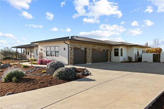 view of front of home featuring driveway, an attached garage, a gate, fence, and stucco siding