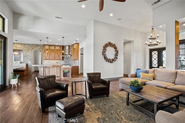 living area with dark wood-style floors, ceiling fan with notable chandelier, visible vents, and recessed lighting