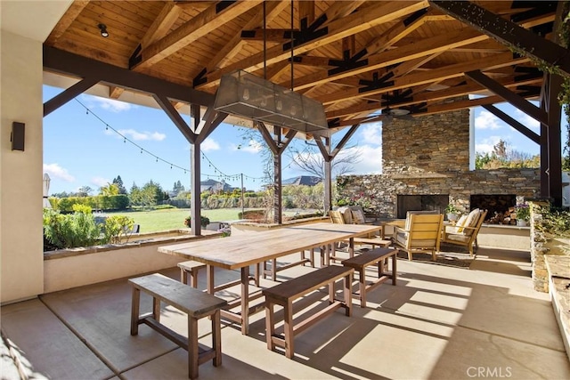 view of patio with an outdoor stone fireplace, ceiling fan, and outdoor dining area