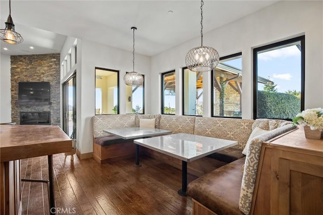 living room featuring a stone fireplace, breakfast area, and hardwood / wood-style flooring