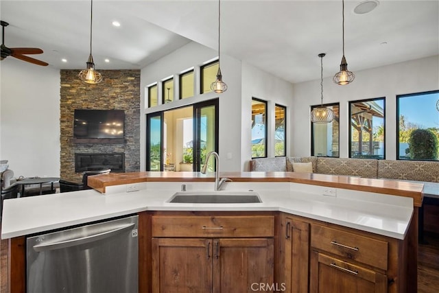 kitchen with decorative light fixtures, light countertops, stainless steel dishwasher, open floor plan, and a sink