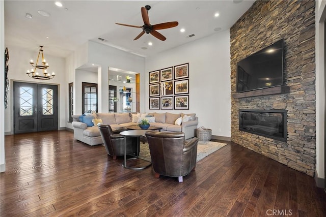 living area featuring a stone fireplace, wood-type flooring, visible vents, and baseboards