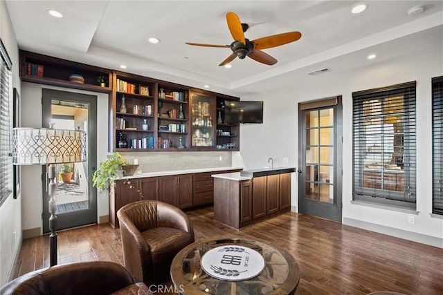 bar with dark wood-style floors, a tray ceiling, visible vents, and recessed lighting