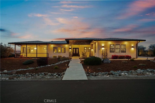 view of front of property featuring a standing seam roof, metal roof, and stucco siding