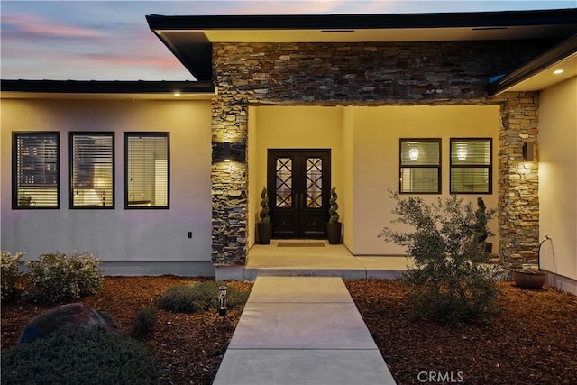 exterior entry at dusk with stone siding and stucco siding