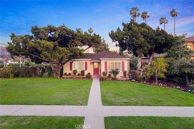 view of front of home with stucco siding and a yard