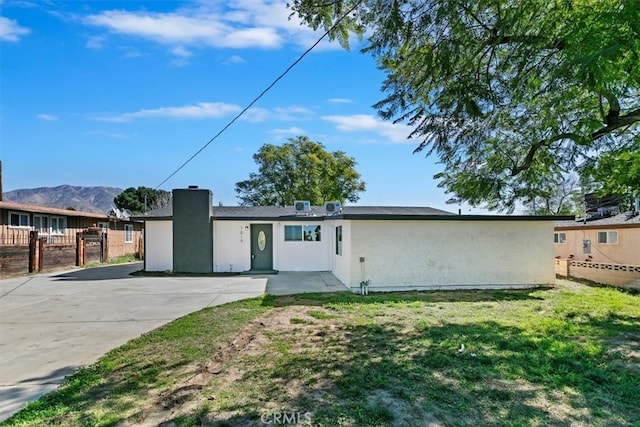 view of front of property with a front yard, fence, and stucco siding