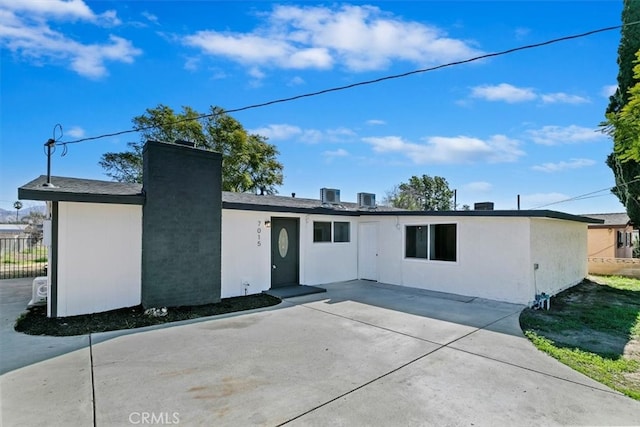 view of front of home with stucco siding, central AC, fence, and a patio