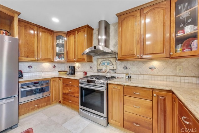 6153 Peridot Ave, Alta Loma, CA 91701 - kitchen with wall chimney range hood, stainless steel appliances, light stone counters, brown cabinets, and decorative backsplash