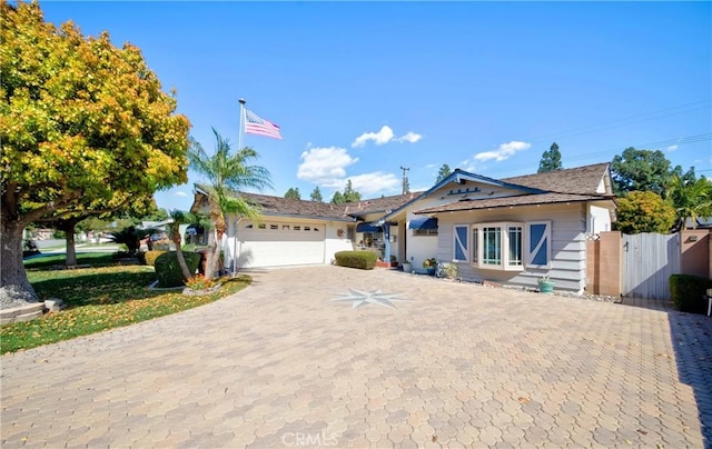 view of front of house featuring a garage, a gate, fence, and decorative driveway