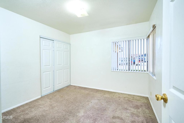 unfurnished bedroom with carpet, a closet, and baseboards