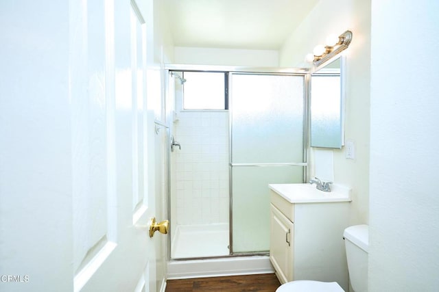 bathroom featuring vanity, wood finished floors, a shower stall, and toilet