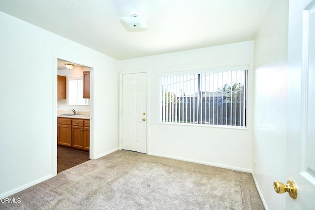 carpeted spare room with a sink and baseboards