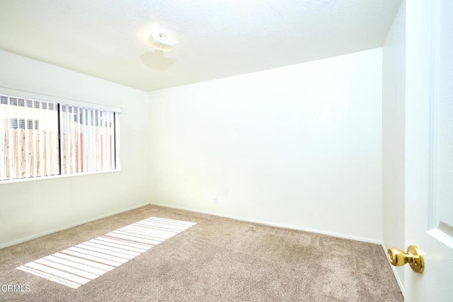 unfurnished room with carpet flooring and baseboards