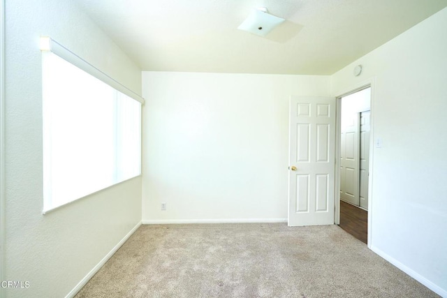 carpeted empty room featuring baseboards