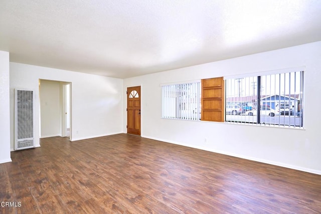 unfurnished room with visible vents, baseboards, and dark wood finished floors