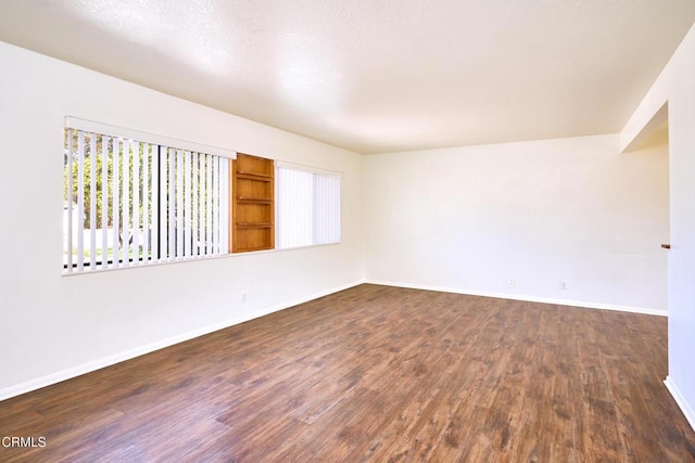 empty room with baseboards and dark wood-style flooring