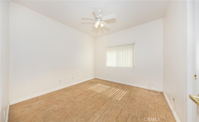 unfurnished room with light wood-type flooring, a ceiling fan, and baseboards