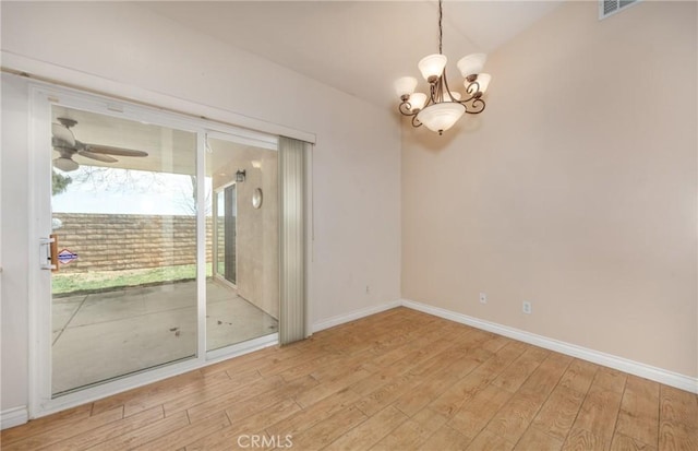 spare room with ceiling fan with notable chandelier, visible vents, baseboards, and wood finished floors