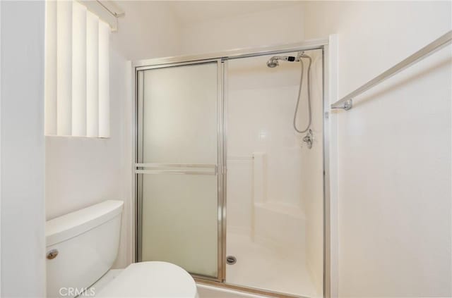 full bath featuring a shower stall and toilet