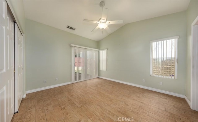 unfurnished bedroom featuring lofted ceiling, light wood-style flooring, visible vents, baseboards, and a closet