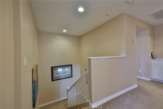 corridor with visible vents, carpet, an upstairs landing, and baseboards