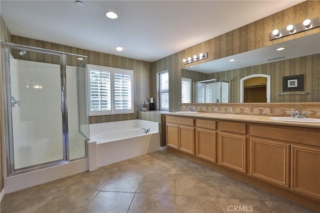 full bath with a sink, a shower stall, a bath, and wallpapered walls