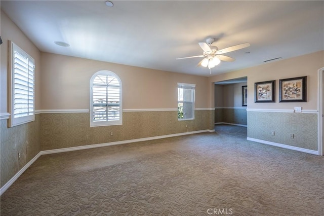 unfurnished room with a healthy amount of sunlight, wallpapered walls, carpet, and ceiling fan