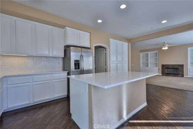 kitchen featuring stainless steel fridge, a kitchen island, light countertops, and dark wood-style flooring